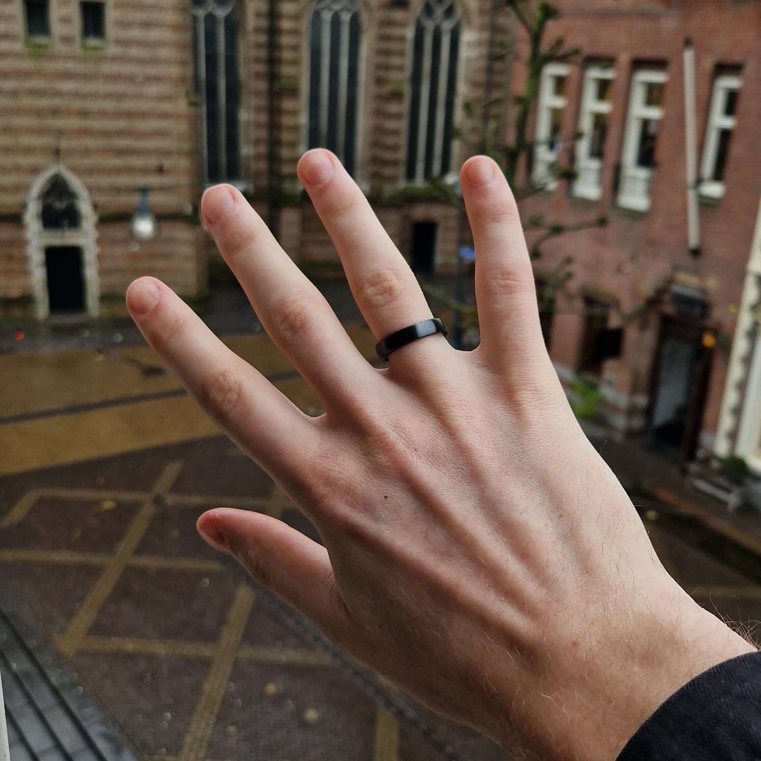 Hand with Astari Atlantis contactless payment ring against a backdrop of historic architecture.
